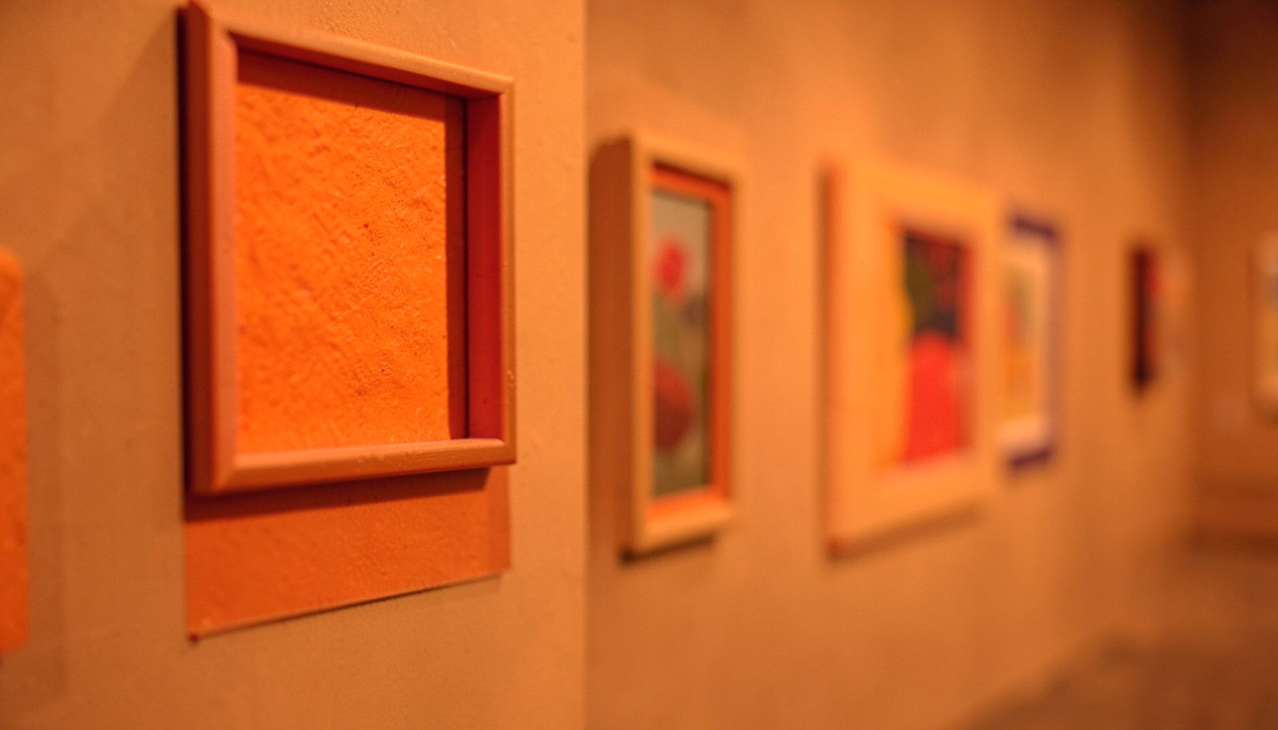 An illustration exhibition space with framed artwork on warm gallery walls