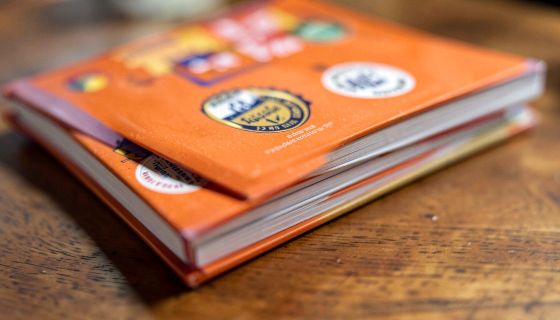 A stack of children's books with award stickers on their covers, on a wooden table